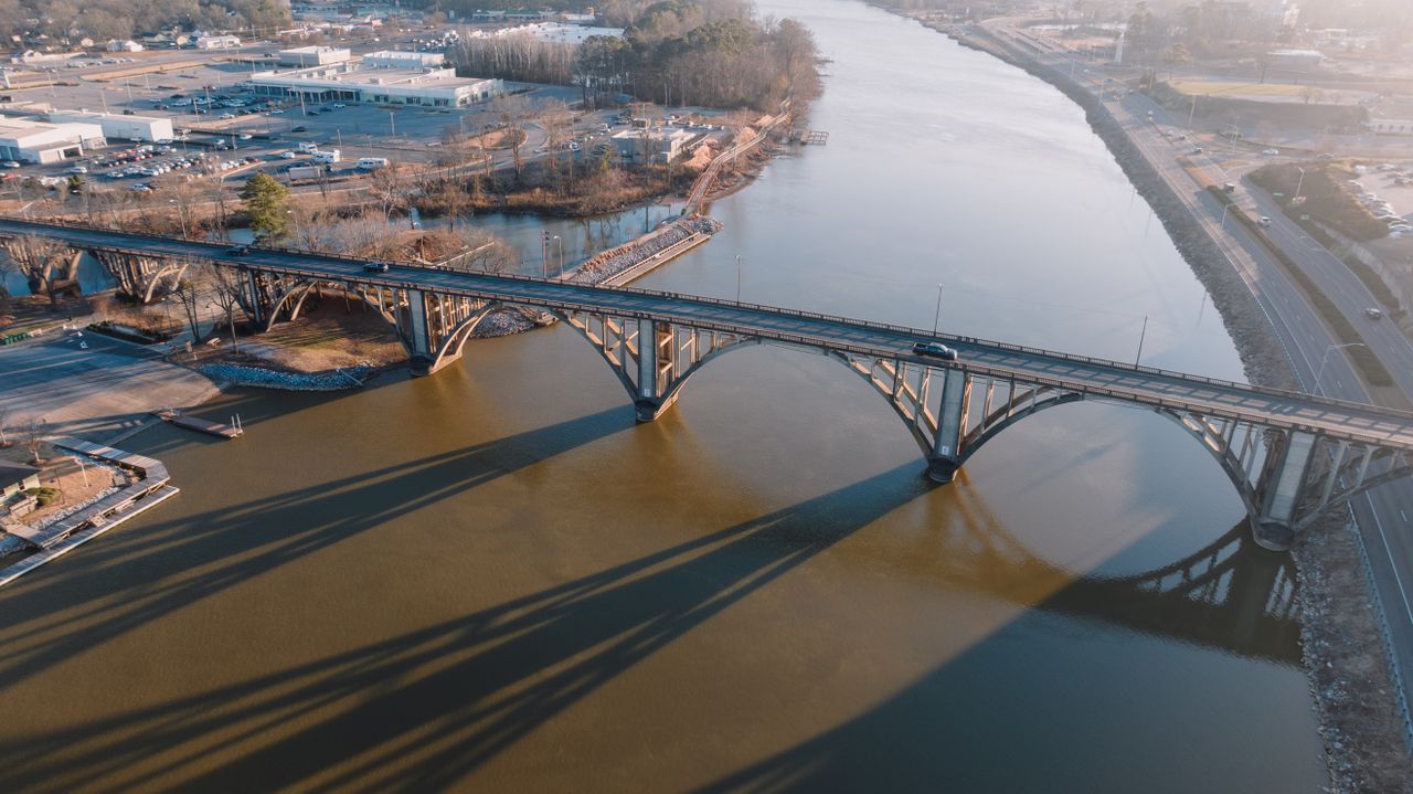 Stunning Aerial Shot Of A Bridge Crossing Over A Calm River